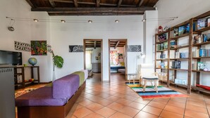 A spacious living area with a sofa, a bookshelf, a television, and a plant. - In Barberia- Cozy Corner (Milis)