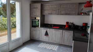 Una cocina moderna con armarios grises, horno empotrado, hervidor rojo y encimera negra.