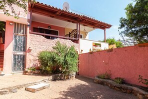 A residential building with a red exterior, a satellite dish, a balcony, and a stone wall. - Josto Panoramic- Sea view (Cuglieri)