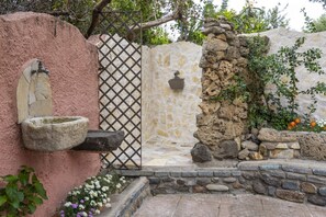 A rustic stone wall with a metal gate, a stone well, and a stone wall with climbing plants. - Josto Panoramic- Sea view (Cuglieri)