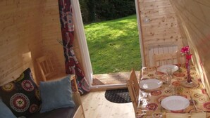 Une cabane en bois avec un petit coin repas et un canapé agrémenté de coussins.