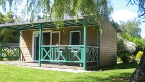 Une petite cabane en bois avec un porche vert et une cour clôturée.