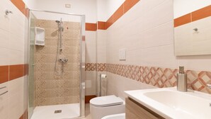 Une salle de bain avec douche, toilettes et lavabo.