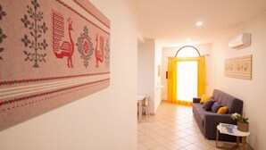 Un salon avec un canapé, une petite table et un climatiseur fixé au mur.