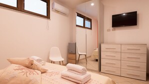 Une chambre à coucher comprenant un lit, une chaise, une commode, un téléviseur et un miroir.