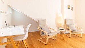 A modern room with a white desk, two grey chairs, a small side table, and a lamp. - Casa Sofia-Modern Apartment (Oristano)