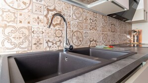 Une cuisine dotée d’un évier à deux bacs, d’un crédence décorée et de meubles de rangement modernes.