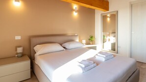 Une chambre à coucher comprenant un lit, des tables de chevet, une commode, un miroir et un luminaire au plafond.