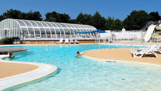 A swimming pool with a sandy area and lounge chairs, a covered structure, and a water slide. - Mobile home 26m² with terrace in Soustons, nature camping (Soustons)