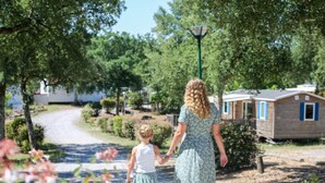 A woman and a child walking on a gravel path in a campsite with mobile homes in the background. - Mobile home 26m² with terrace in Soustons, nature camping (Soustons)