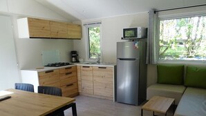 Una cucina compatta con mobili in legno, un frigorifero in acciaio inossidabile, un forno a microonde e un'area pranzo con tavolo e sedie.