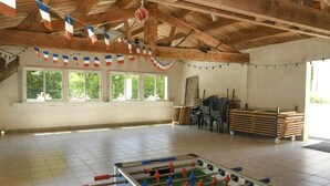 Ambiente interno con tavolo da calcio, travi in legno e finestre con tende.