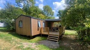 Una baita di legno con una veranda e una zona salotto all'aperto coperta.