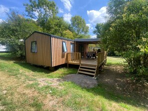 Eine Holzhütte mit einer Terrasse und einem überdachten Sitzbereich im Freien.