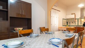 A dining area with a table set for four, chairs, a wooden cabinet, and a kitchen area with a microwave.