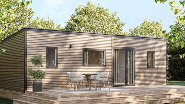 Una casa móvil de una sola planta, moderna, con un porche, dos ventanas y una puerta corrediza de vidrio.