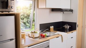 Una cocina compacta con microondas, lavavajillas y ventana con vistas al verdor.