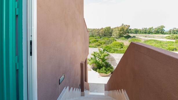 A staircase leading to a balcony with a view of greenery and a distant landscape. - Casa Tatti- Calm&Natural (San Giovanni di Sinis)