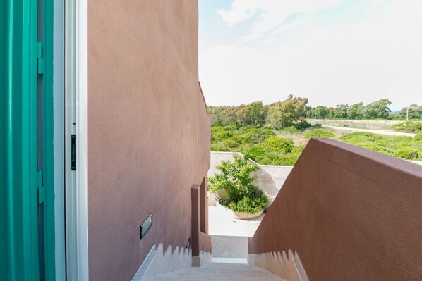 Una escalera que lleva a un balcón con vistas a zonas verdes y un paisaje lejano.