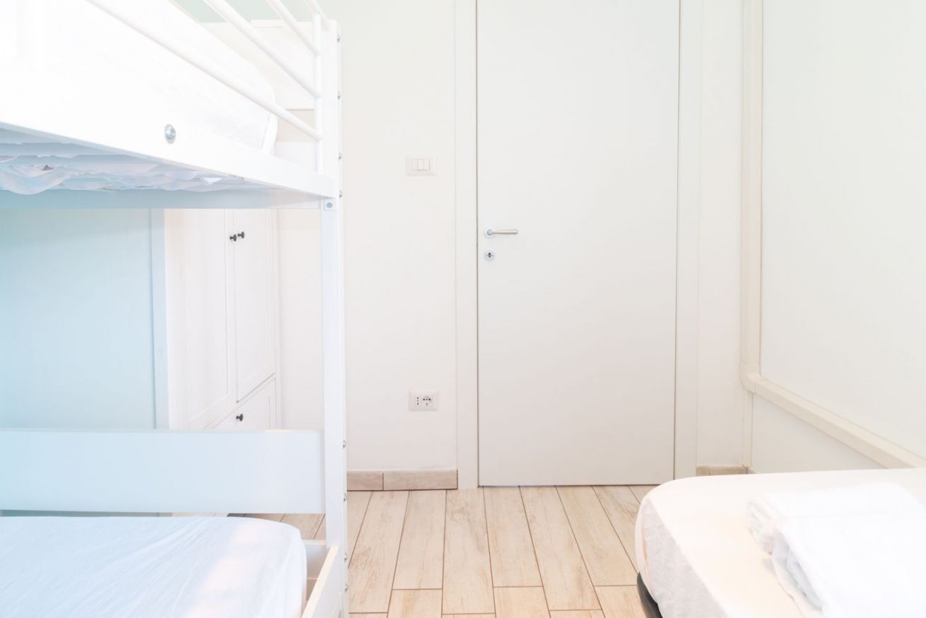 A room with bunk beds, a wardrobe, and a door.
