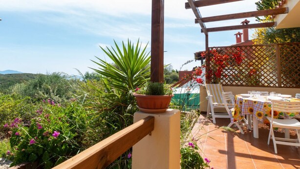 Una terraza con mesa lista para comer, rodeada de follaje y vistas a las colinas.