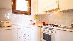 Una cocina con armarios blancos, una ventana, un tostador, una estufa y un lavamanos.