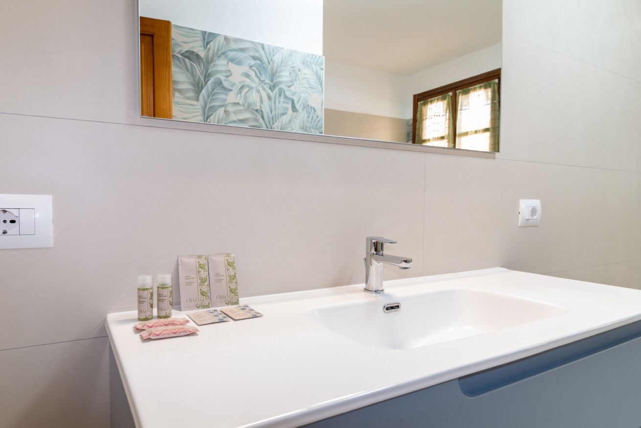 A bathroom with a white sink, a mirror, and toiletries on the counter.
