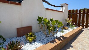 A garden with white pebbles, plants, and a wooden fence. - Casa S'Architteddu- Coastal Escape (San Vero Milis)