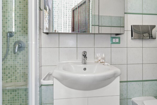 A bathroom with a sink, mirror, and shower.
