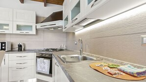 A modern kitchen with white cabinetry, a built-in oven, a gas stove, and a stainless steel sink. - Casa S'Architteddu- Coastal Escape (San Vero Milis)