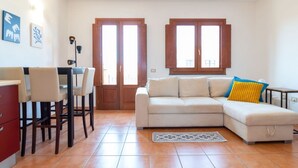 Een woonkamer met een bank, stoelen, een tafel en een vloerkleed.