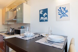 A modern kitchen with a dining table set for two, a microwave, and a gas stove.