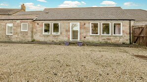 A stone building with a gravel driveway, a wooden gate, and a clear sky. - Cheviot - North East Escapes (Wooler)