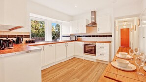 A modern kitchen with white cabinets, a wooden countertop, and a built-in oven. - Cheviot - North East Escapes (Wooler)