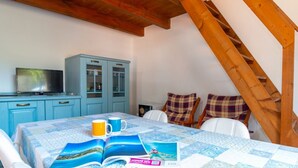 Een gezellige kamer met een houten trap, een tafel met een sprei, een televisie en een kast.