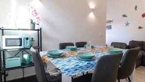Ein Essbereich mit einem Tisch für vier Personen, Stühlen, einer Mikrowelle und einem Blumentopf.