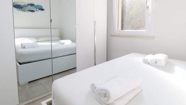 Ein modernes Schlafzimmer mit Bett, Spiegel, Kleiderschrank und Fenster.