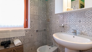 A bathroom with patterned tiles, a bidet, a sink, and a towel rack. - Appartamento Azzurro-Lovely&Quiet (Oristano)