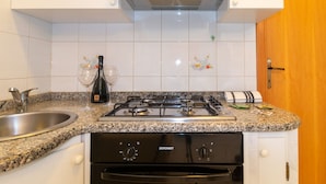 A kitchen with a gas stove, stainless steel sink, and white cabinets. - Appartamento Azzurro-Lovely&Quiet (Oristano)