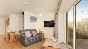 Un salon moderne avec un canapé en cuir, une table basse en bois et un téléviseur fixé au mur.