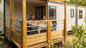 Eine Holzterrasse mit Tisch und Stühlen, mit Blick auf einen Garten.