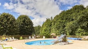 A swimming pool with a slide, surrounded by lounge chairs and a forested hillside. - Chalet with Terrace for 6 people in Bieuzy (Bieuzy)