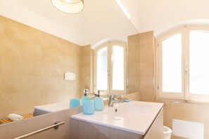 Ein Badezimmer mit einem großen Waschbecken, zwei Spiegeln, einem Handtuchhalter und einer Duschkabine.