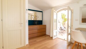 A room with a wooden floor, a white door, a wooden dresser, a mirror, and a chair.