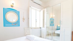 A bedroom with a bed, a mirror, a starfish decoration, and a door leading to a balcony. - Casa dei Catalani-Rustic Charm (Torre Grande)