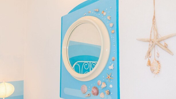 A wall with a mirror surrounded by seashells and starfish. - Casa dei Catalani-Rustic Charm (Torre Grande)