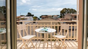 Een balkon met een tafel en twee stoelen, met uitzicht op een woongebied.