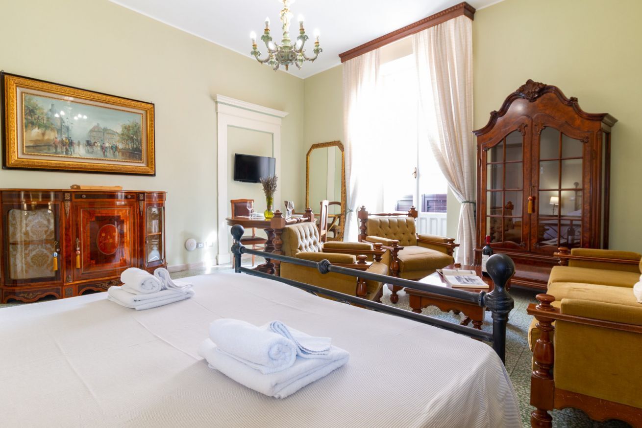 Une chambre d’hôtel avec un grand lit, une armoire en bois, une télévision et un balcon avec vue.