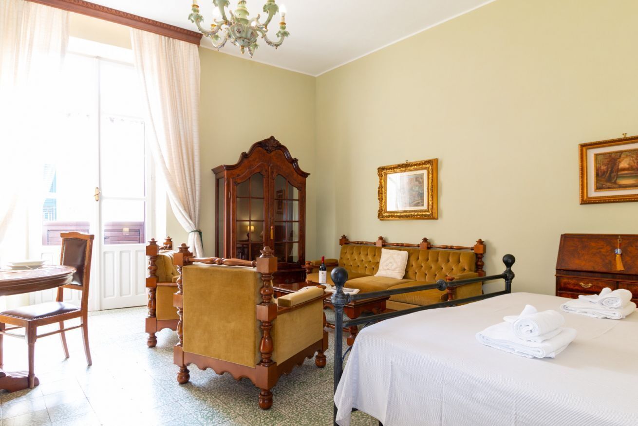 Une chambre d’hôtel avec un lit, une chaise en bois, une table et un grand miroir.