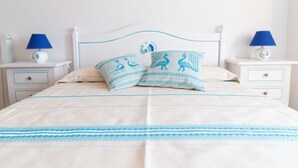 A bed with a white and blue striped bedspread, two matching pillows, and two bedside tables with lamps. - Cocco e Dessì Home- Mattia (ORISTANO)